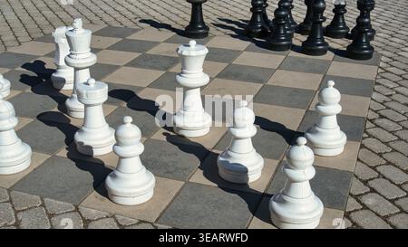 Strategisches Outdoor-Riesenschachspiel mit großen weißen und schwarzen Teilen Stockfoto