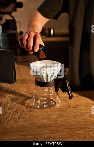 Nahaufnahme eines frisch gemahlenen Kaffees, der aus einer Mahlmaschine direkt in einen Metallportafilter gegeben wird Stockfoto