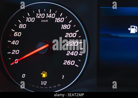 Moderner Tachometer im Armaturenbrett im Auto bei Nacht. Die Warnleuchte für niedrigen Kraftstoffstand leuchtet auf dem Display auf Stockfoto