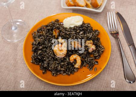 Paella ist eine Variante des Gerichts aus schwarzem Reis und Meeresfrüchten Stockfoto