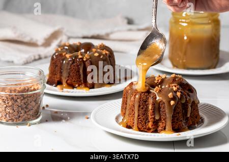 Karamellsauce wird auf frisch gebackenen klebrigen Toffee Pudding Kuchen löffelt. Stockfoto