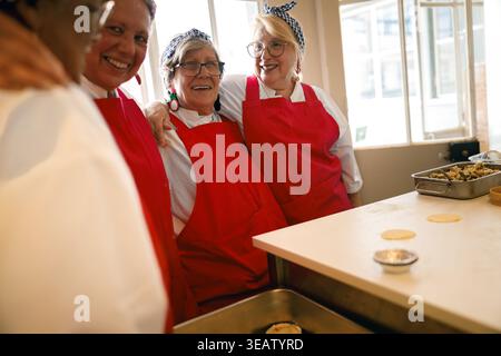 Seniorinnen teilen sich einen spielerischen Moment beim Backen in einer hellen Küche Stockfoto