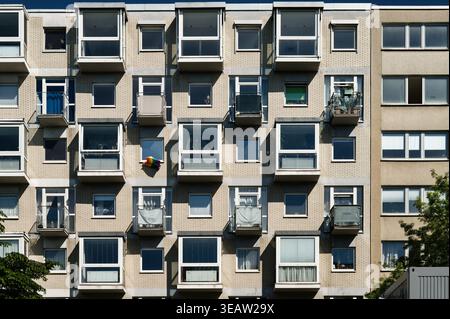 Geometrischer Blick auf eine Gebäudefassade in Köln. Urban Living mit versetzten Balkonen, Glasfronten und einer kleinen Stolz-Flagge als farbenfrohen Akzent. Stockfoto