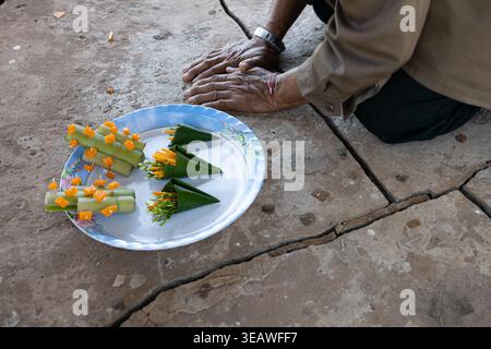 Nahaufnahme der Hände eines alten laotischen Mannes, der sich im alten buddhistischen Tempel um Segen mit Kerzen und Blumen niederwarf. Wat Pho Sri, Laos. Stockfoto