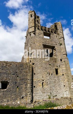 Ruine des Turms von Middleham Castle, der sich gegen einen blauen Himmel mit Kumuluswolken erhebt Stockfoto