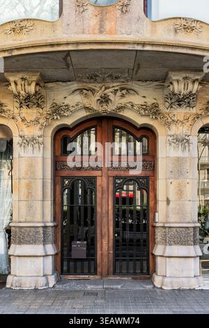 Verzierte Art-Nouveau-Holztür und schmiedeeiserne Eingangstür mit dekorativen Steinmetzarbeiten an einer historischen Gebäudefassade Stockfoto