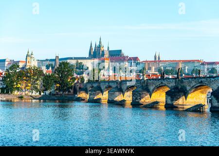 Atemberaubendes Panorama von Prag mit der historischen Karlsbrücke, die sich über die Moldau erhebt, eingerahmt von der majestätischen Prager Burg unter einem klaren blauen Himmel, die die reiche Architektur der Stadt zeigt. Stockfoto