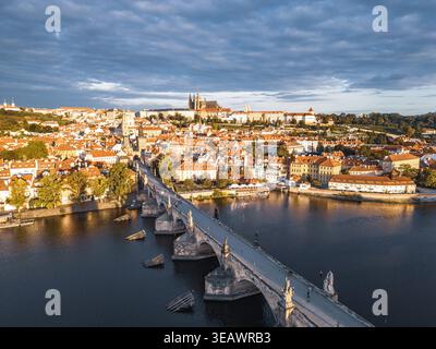 Das Morgenlicht strahlt ein warmes Leuchten über die historische Karlsbrücke und die Prager Burg aus. Die Moldau spiegelt die wunderschöne Skyline der Altstadt wider und schafft eine malerische Szene. Stockfoto
