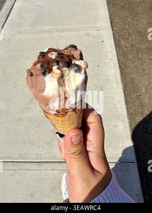 Eine Person, die an einem sonnigen Tag, dem 24. April 2026, in Surrey, British Columbia, Kanada, eine in Schokolade getauchte Nestlé Drumstick Eiscreme hält. Stockfoto