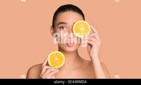 Frau hält Orangenscheiben in einer kreativen Collage auf einem einfachen Hintergrund Stockfoto