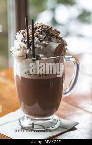 Tasse heiße Schokolade mit Schlagsahne und zwei Trinkhalmen. Stockfoto