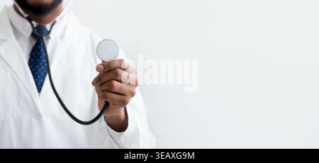 Männlicher Arzt hören mit Stethoskop über hellen Hintergrund Stockfoto