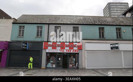 Mackem Merch befindet sich an der Sunderland High Street. Das Geschäft verfügt über ein auffälliges Schild mit Namen und Schriftzug. Eine Person in Arbeitsuniform wird außerhalb des Stores gesehen. Die Gegend scheint ruhig zu sein und mehrere Ladenfronten sind vorhanden, einige davon geschlossen, was auf das lokale Einzelhandelsumfeld hinweist. Stockfoto