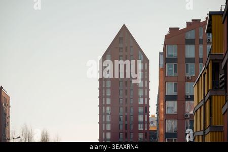 Moderne Terrakotta-Apartmenthäuser vor dem Sonnenuntergang. Wohnviertel mit hohen und niedrigen Gebäuden an einem sonnigen Winternachmittag. Stockfoto
