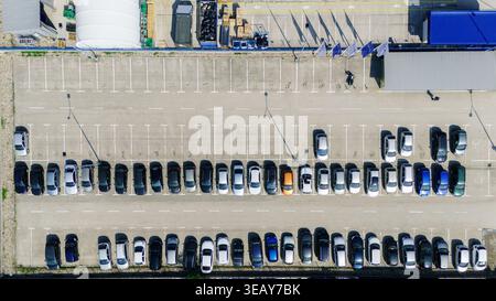 Luftaufnahme eines großen Parkplatzes mit Reihen geparkter Autos und weißen Markierungen auf dem Asphalt in Sremska Mitrovica, Vojvodina, Serbien. Stockfoto