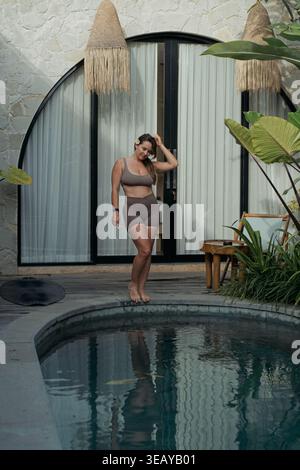 Sorglose Frau, die Frangipani am Pool der Villa hält, Canggu, Bali Stockfoto