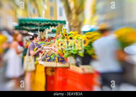 An einem lebhaften Marktstand unter freiem Himmel werden frische Sonnenblumen und Blumensträuße angeboten Stockfoto