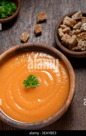 Eingeäscherte Karottensuppe auf einem rustikalen Holztisch Croutons an der Seite. Stockfoto