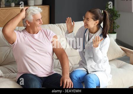 Schwester, die nach der Injektion zu Hause Pflaster auf Senioren auflegt Stockfoto