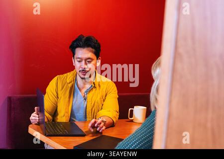 Asiatischer Geschäftsmann, der sich auf einem Laptop teilt Stockfoto