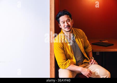Junge asiatische Kreativen sitzen an einem Schreibtisch im Büro Stockfoto