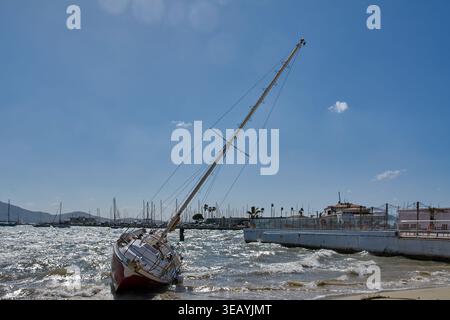 Mallorca Spanien - 24. April 2026: Ein Segelboot mit hohem Mast liegt an der Sandküste von Puerto Pollenca nach einem heftigen Sturm mit der Stockfoto