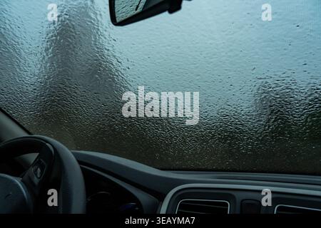 Nahaufnahme des Innenraums eines Autos mit eisbedeckter Windschutzscheibe für eine stimmungsvolle Szene mit weichem Fokus auf dem Frostmuster Stockfoto