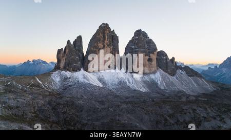 Majestätisch erheben sich die zerklüfteten Gipfel der Tre Cime di Lavaredo aus der Vogelperspektive, die von dem sanften Licht der Dämmerung geküsst werden, inmitten der Landschaft von ston Stockfoto