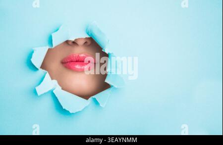 Kreative Collage, die Lippen durch gerissenes Papier auf blauem Hintergrund in einer künstlerischen Umgebung zeigt Stockfoto