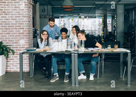 Gruppe junger Leute, die an einem Projekt in einem modernen Arbeitsbereich während des Tages zusammenarbeiten Stockfoto