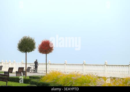 Eine ruhige Uferszene mit einem Mann neben seinem Fahrrad in einer ruhigen Parklandschaft Stockfoto