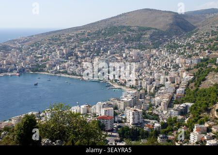 Großer Panoramablick auf Saranda, eingebettet zwischen dem Ionischen Meer und sanften Hügeln unter einem klaren blauen Himmel in Albanien Stockfoto