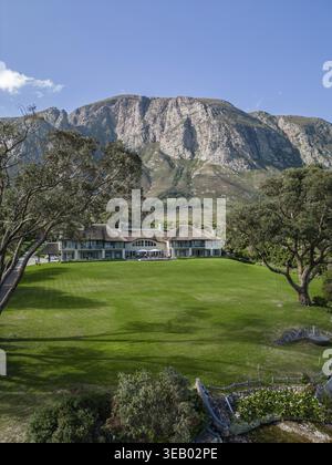 Großes Haus am Fuße des hohen felsigen Berges, Gebäude, hellgrün idealer Rasen, Hotelgebiet. Hermanus Klein Lagune, Kleinriversvlei, Fluss Stockfoto