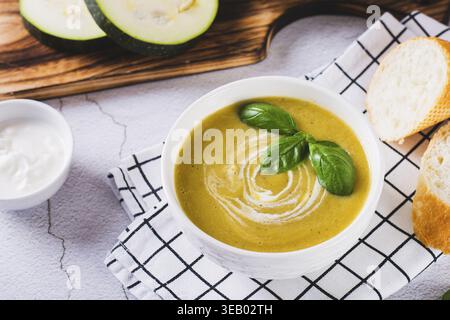 Köstliches Zucchini-Suppe-Püree in einer Schüssel und Brotstücke auf dem Tisch Stockfoto