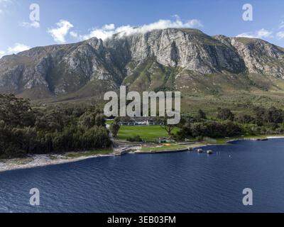 Küstenlandschaft der Bucht, hellgrüner Rasen, Hotelgebiet, blaues Wasser. Oktober in der Hermanus Klein River Lagune, Kleinriversvlei, Riversvlei, Südafrika Stockfoto