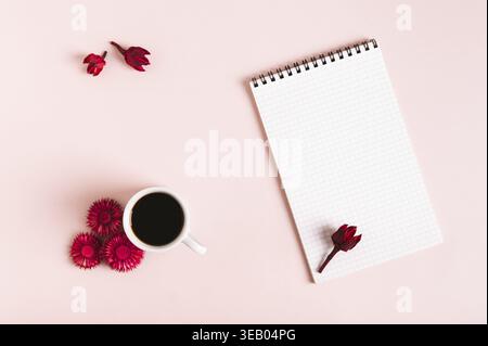 Tasse Kaffee, getrocknete Blumen und offenes Notizbuch auf rosafarbenem Hintergrund von oben Stockfoto