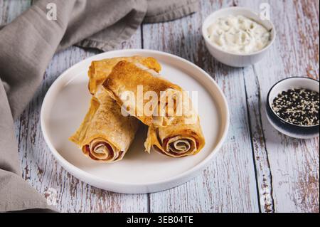 Tortilla, Schinken und Käse in gebackenen Brötchen auf einem Teller auf dem Tisch Stockfoto