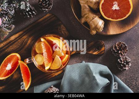 Duftender Tee mit Orangen- und Ingwerstücken in einer Tasse auf dem Tisch Stockfoto