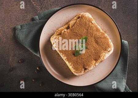 Nahaufnahme eines klassischen Tiramisu-Desserts mit Keksen, Mascarpone und Kaffee auf einem Teller mit Blick von oben Stockfoto