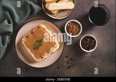 Klassisches Tiramisu-Dessert mit Keksen, Mascarpone und Kaffee auf einem Teller auf dem Tisch mit Blick von der Tischspitze Stockfoto