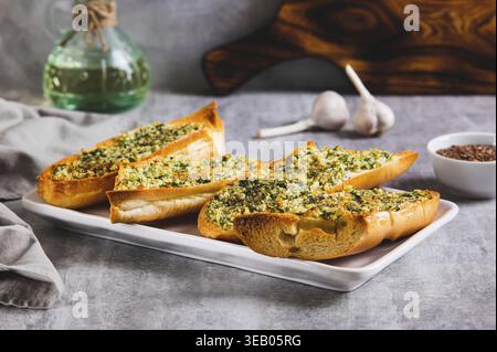 Gebackenes Baguette mit Butter, Knoblauch und Dill auf einem Teller auf dem Tisch Stockfoto