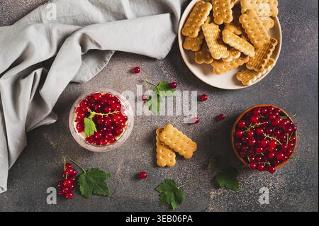 Käsekuchen mit roter Johannisbeere in einem Glas auf dem Tisch mit Blick von der Tischspitze Stockfoto