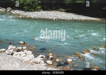 An einem Sommertag fließt ein Gebirgsbach über Felsen Stockfoto
