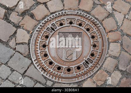 Prag, Tschechisch - 22. August 2013 - Dekorative prager Mannloch-Abdeckung auf Kopfsteinpflasterstraße Stockfoto