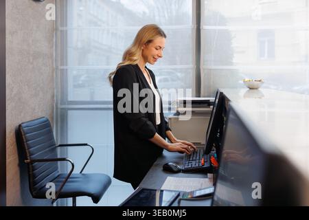 Professioneller Rezeptionist arbeitet an der Rezeption am Computer in der modernen Lobby Stockfoto