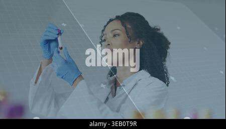 Inspektion eines Wissenschaftlers im Labormantel mit Röhrchen mit roter Probe am Labortisch, mit blauen Handschuhen und HUD Stockfoto