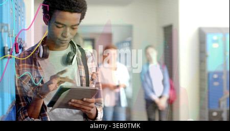 Tapping Tablet asiatischer Teenager mit kariertem Hemd und Kopfhörern im Schulflur mit blauen Schließfächern Stockfoto