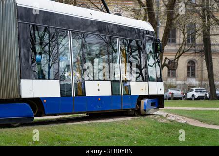 Modernes elektrisches Straßenbahnfahrzeug auf einer Stadtstraße in Riga mit Freileitungen und städtischer Infrastruktur für effizienten und nachhaltigen Stadtverkehr Stockfoto