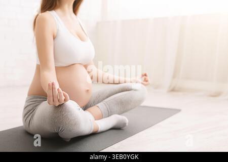 Schwangere Frau übt Yoga in einem hellen, ruhigen Raum auf einer Yoga-Matte Stockfoto