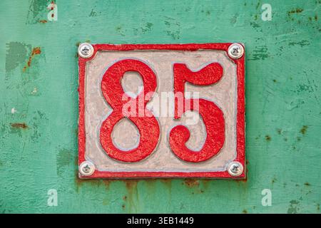Zentriertes, fünfundachtzigjähriges Schild an türkisfarbener Wand. Stockfoto